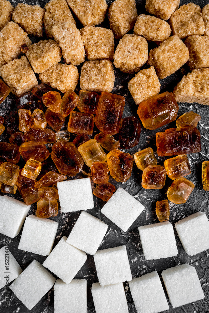 lumps of sugar on dark table background top view pattern