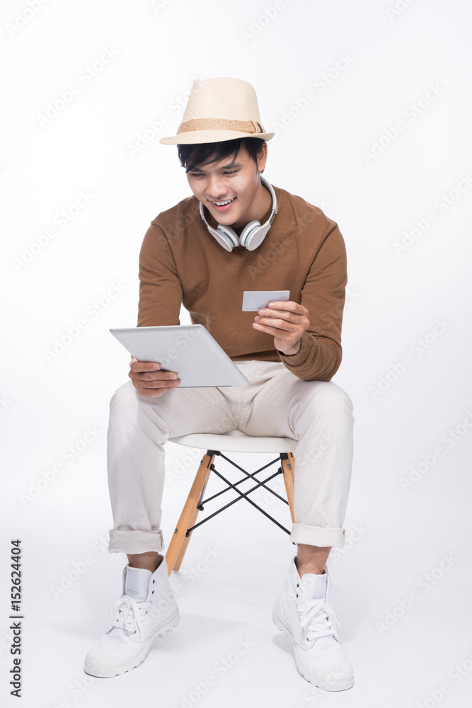 Smart casual asian man seated on chair, shopping online with credit card and smartphon