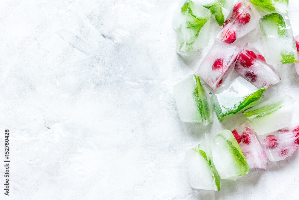 ice cubes with red berries and mint top view gray stone background mockup