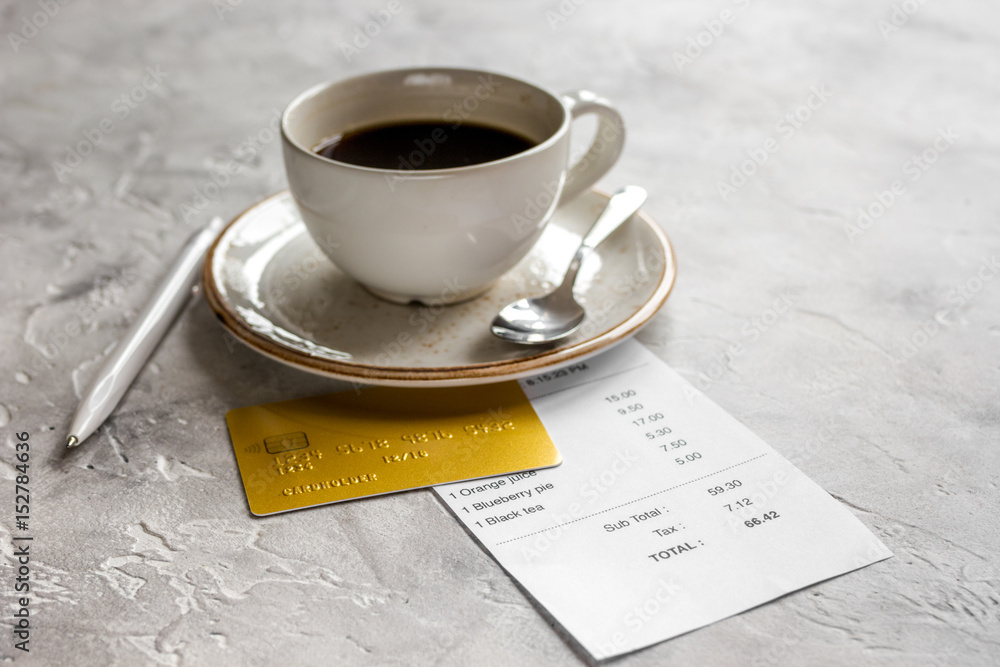 coffee and receipt bill for payment by credit card on stone table background