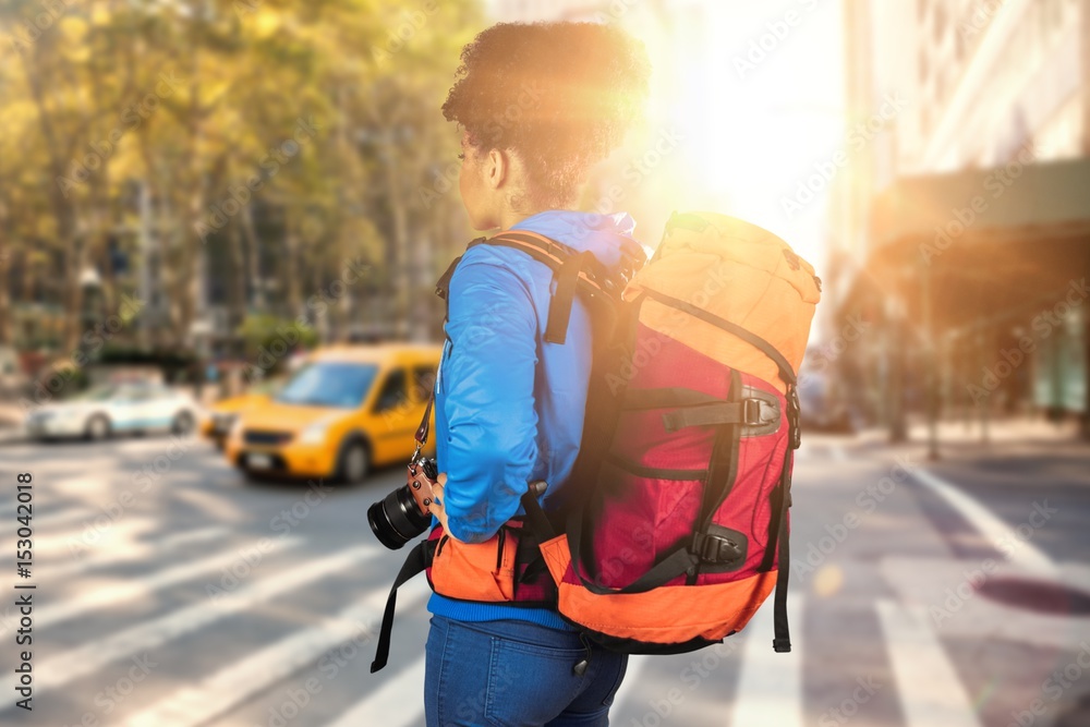 Composite image of young woman with backpack holding camera