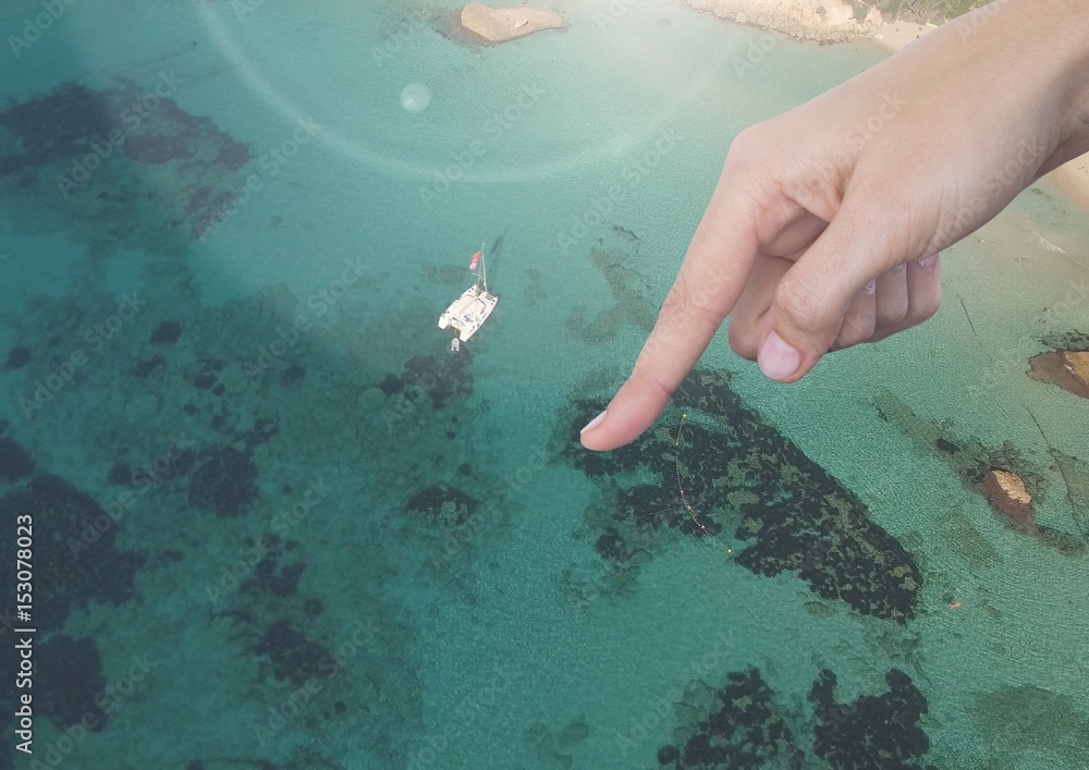 Hand pointing in air over sunny seaside resort