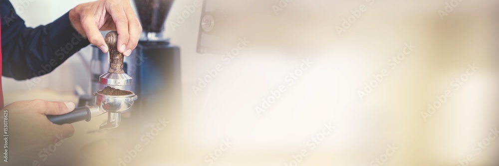 Barista pressing fresh coffee grounds