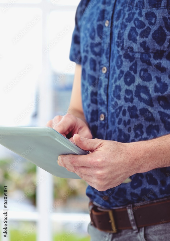 Midsection of male hipster using digital tablet 