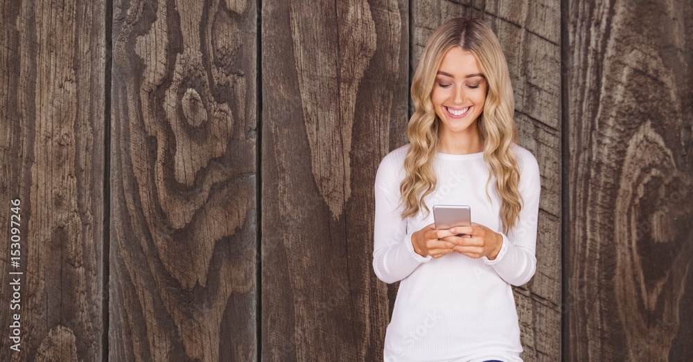 Woman using smart phone against wooden wall