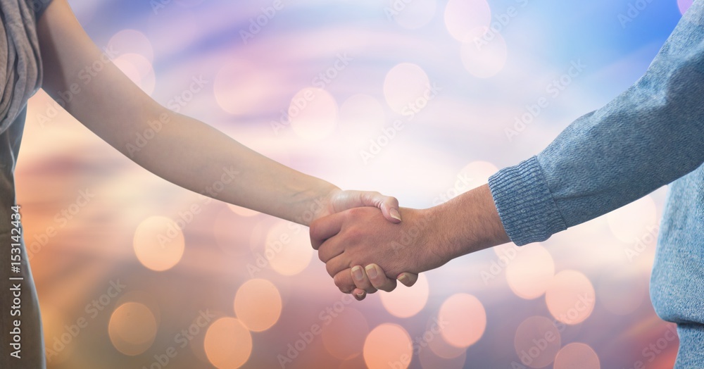 Couple shaking hands against bokeh