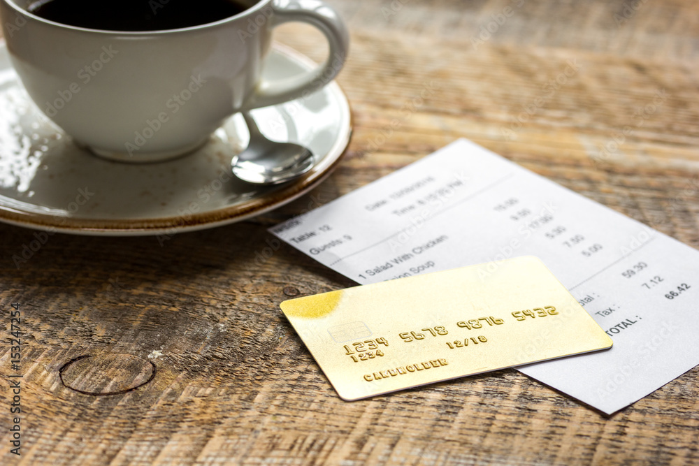 coffee and receipt bill for payment by credit card on wooden table background