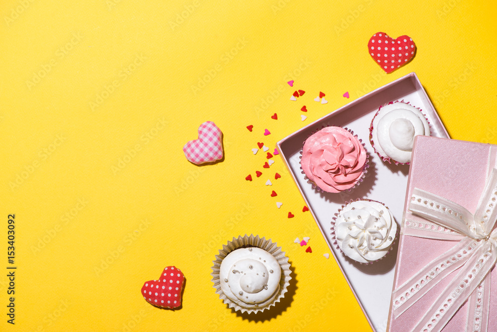 Delicious cupcake with paper box on yellow background