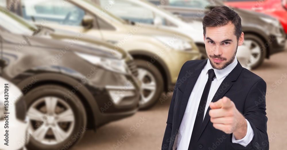 Businessman pointing against car in showroom