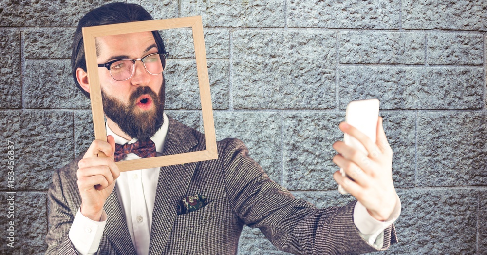 Hipster holding frame while taking selfie on smart phone