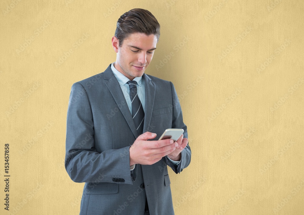 Businessman using smart phone against yellow background