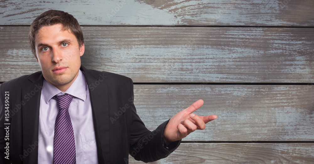 Portrait of businessman shrugging shoulders against wooden wall