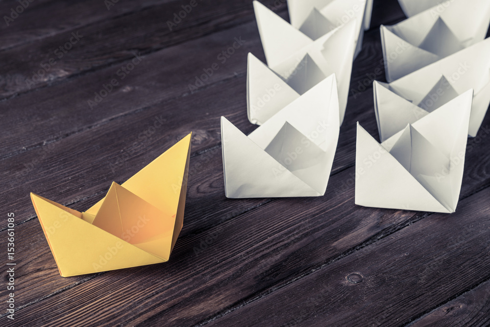 Business leadership concept with white and color paper boats on 