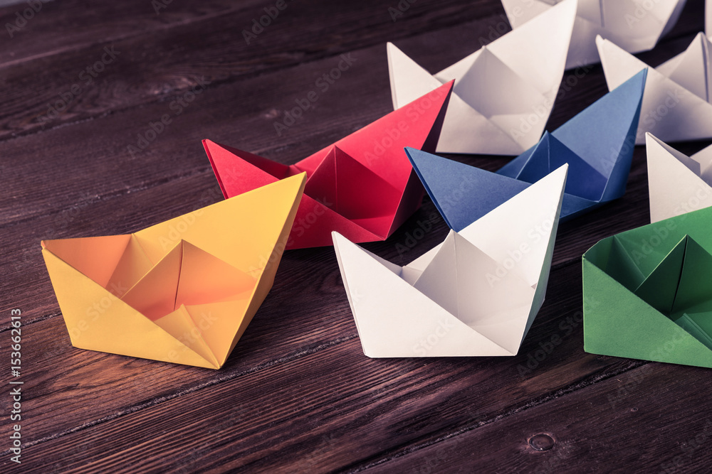 Business leadership concept with white and color paper boats on 