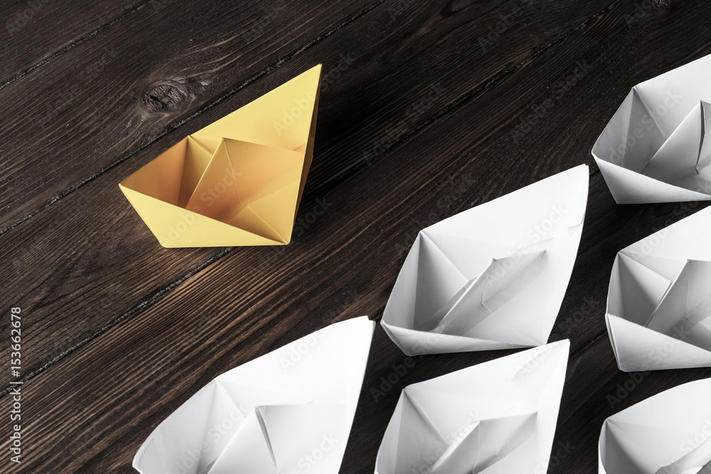 Business leadership concept with white and color paper boats on 