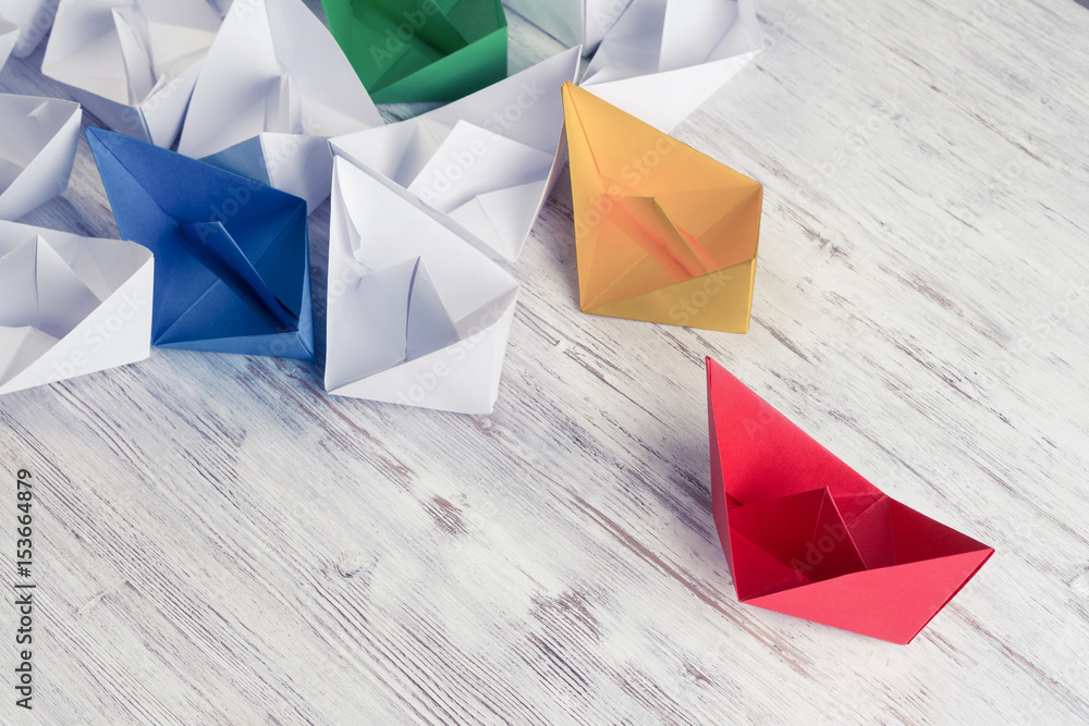 Business leadership concept with white and color paper boats on 