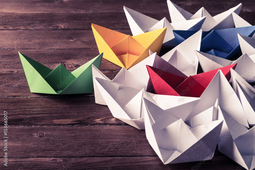 Business leadership concept with white and color paper boats on 