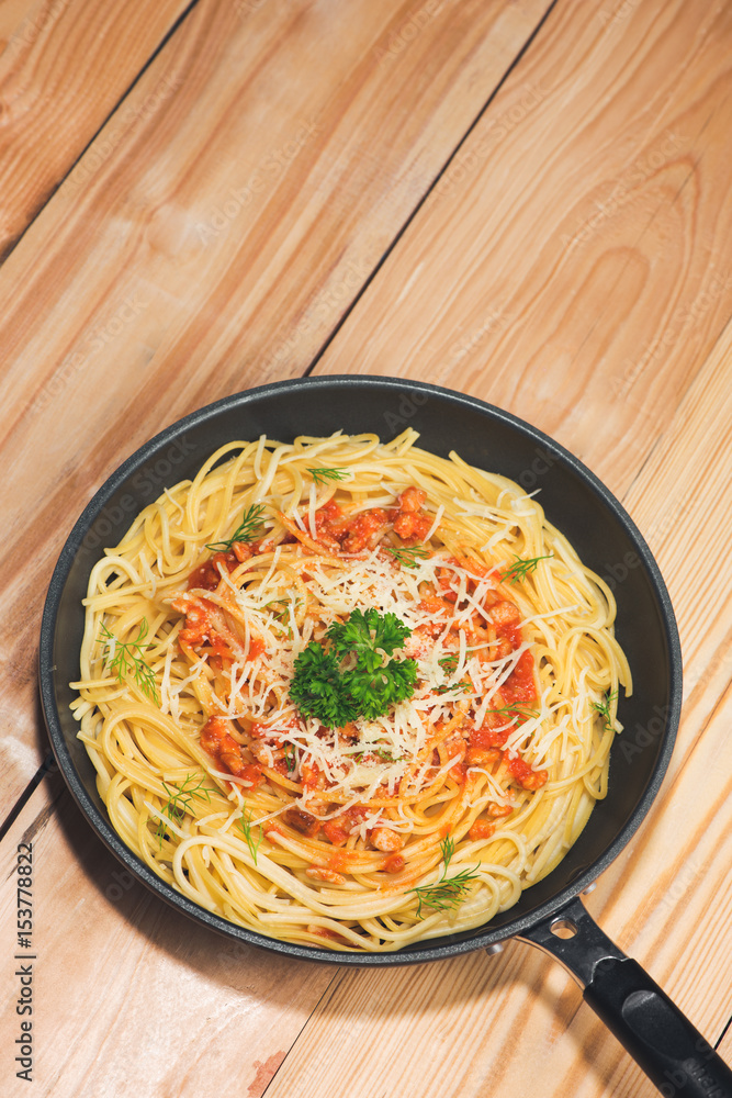 Top view of spaghetti with tomato sauce and meat on wooden table.