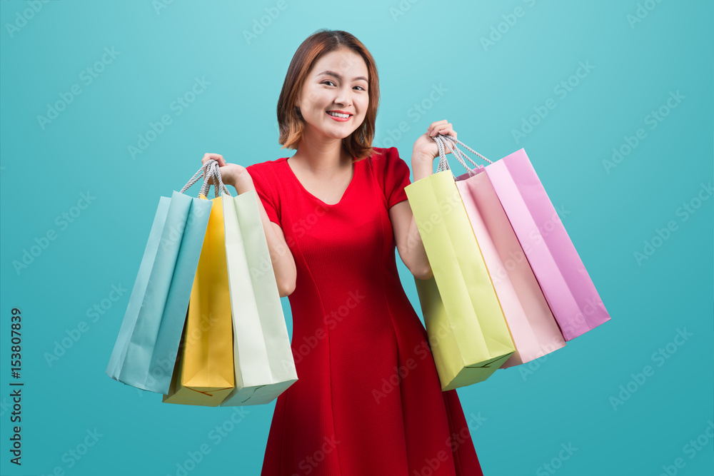 Beautiful young asian woman with colored shopping bags over blue background