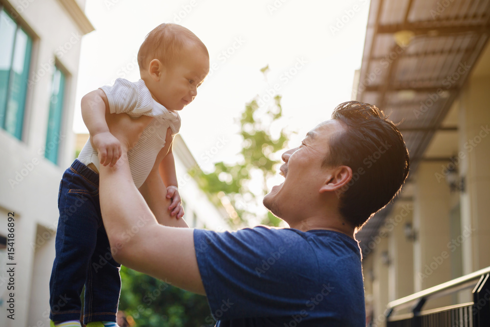 Happy Asian man holding his son to the air