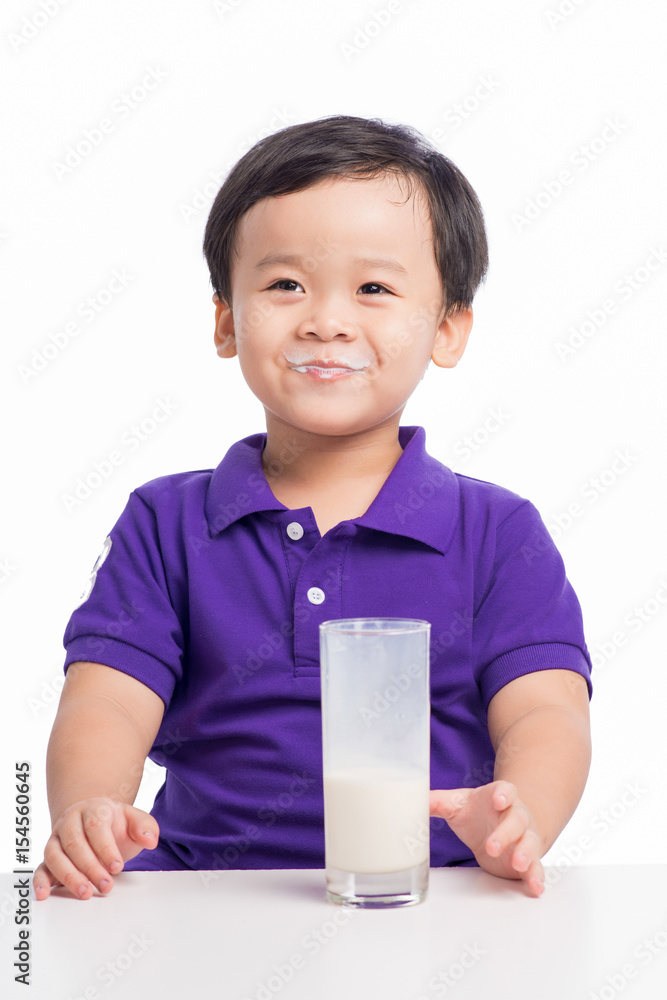 Adorable baby boy with dringking milk with milk mustache holding glass of milk