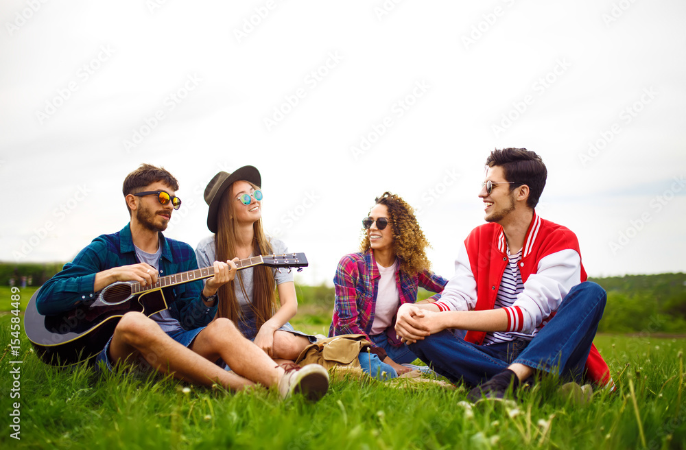 Group of friends enjoying party. The guy plays the guitar. Everyone has a great mood. Summer time. 
