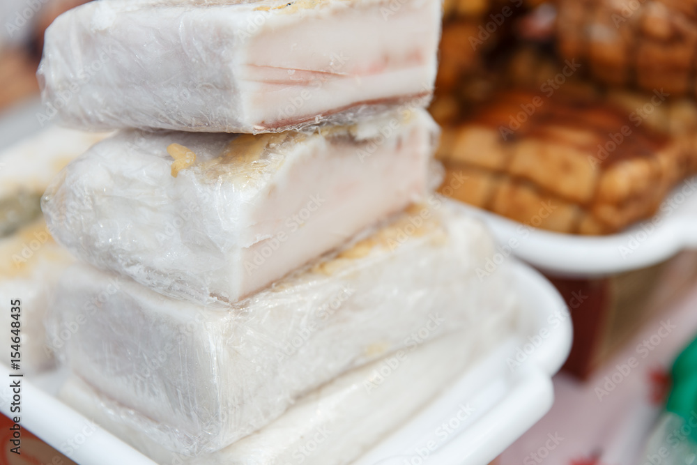 The variety of fresh smoked meat products lying on a stand at the fair.