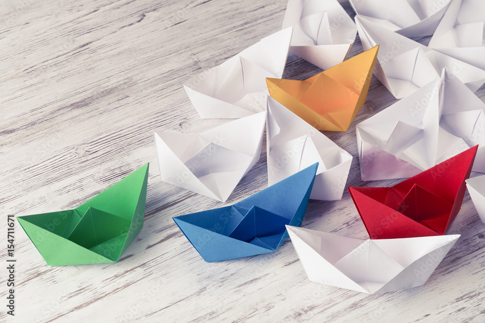 Business leadership concept with white and color paper boats on 