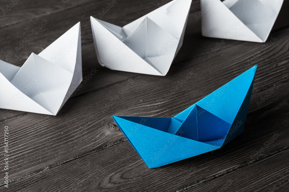 Business leadership concept with white and color paper boats on 