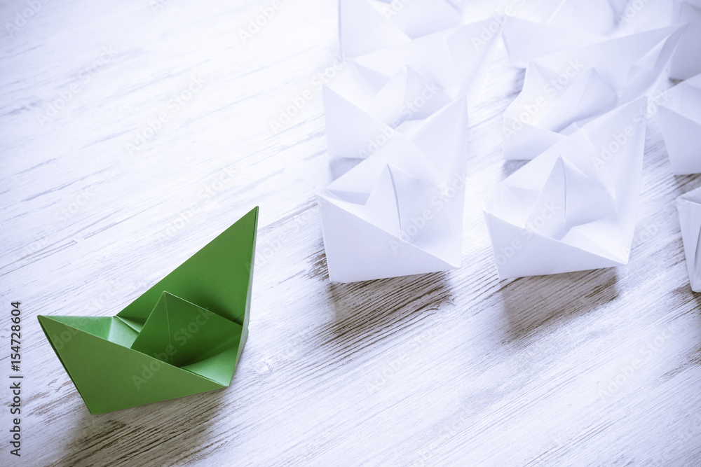 Business leadership concept with white and color paper boats on 