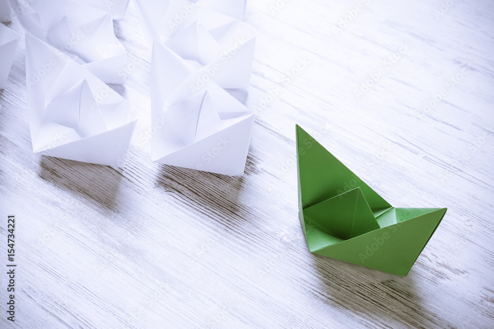 Business leadership concept with white and color paper boats on 