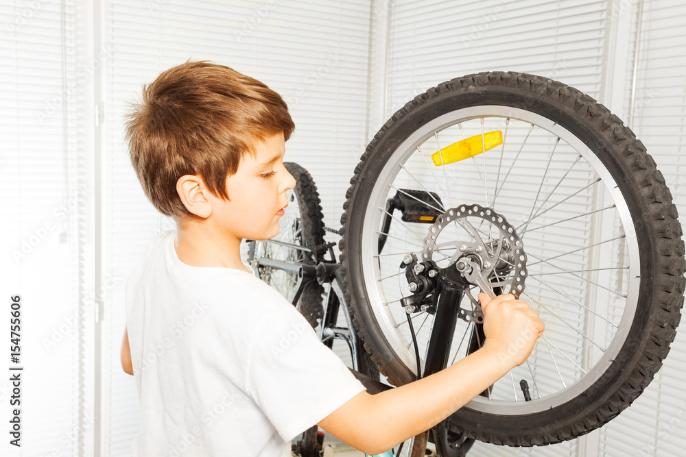 Kid boy repairing his bicycle at garage