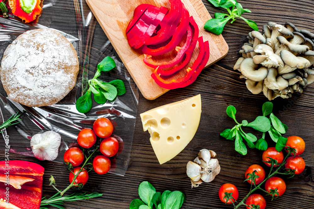 cooking pizza with vegetables and cheese on wooden desk background top view