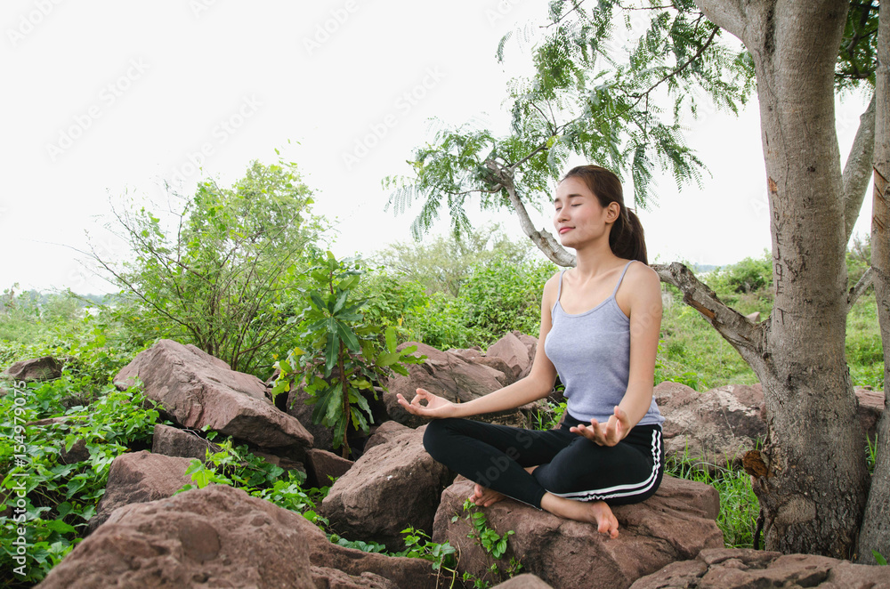 美丽的女人在岩石上做瑜伽