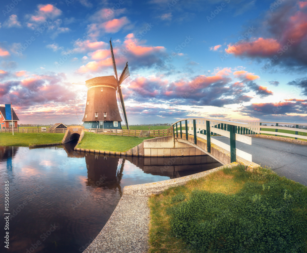 Windmill and bridge near the water canal at sunrise in Netherlands. Traditional dutch windmill and c