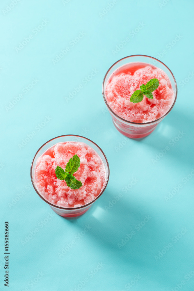 Glass of healthy watermelon juice in summertime on blue background.