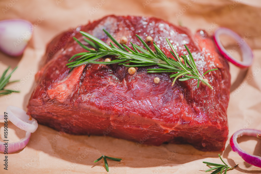 Raw beef on a cutting board  with spices and ingredients for cooking.