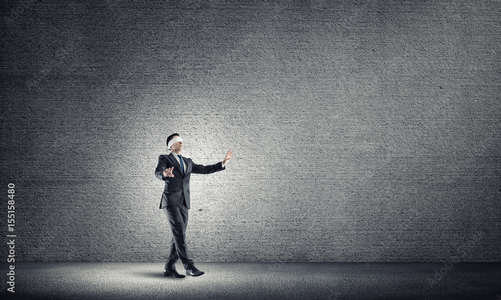 Business concept of risk with businessman wearing blindfold in empty concrete room