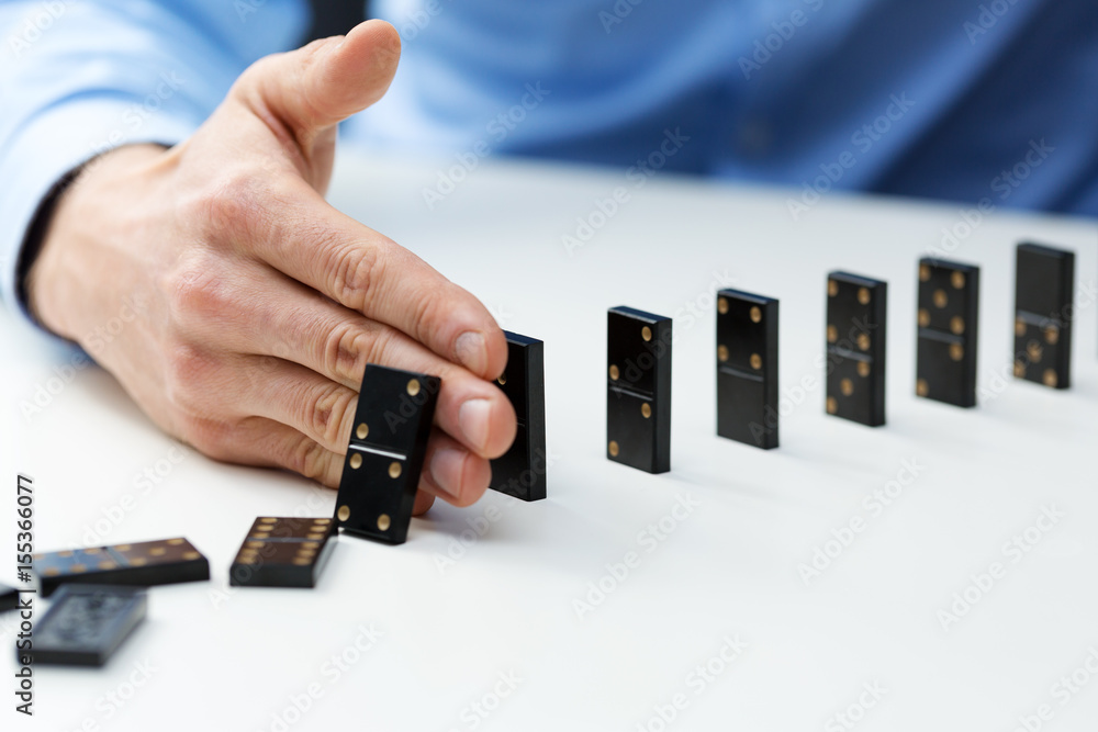 businessman stopping domino effect - business problem solving concept