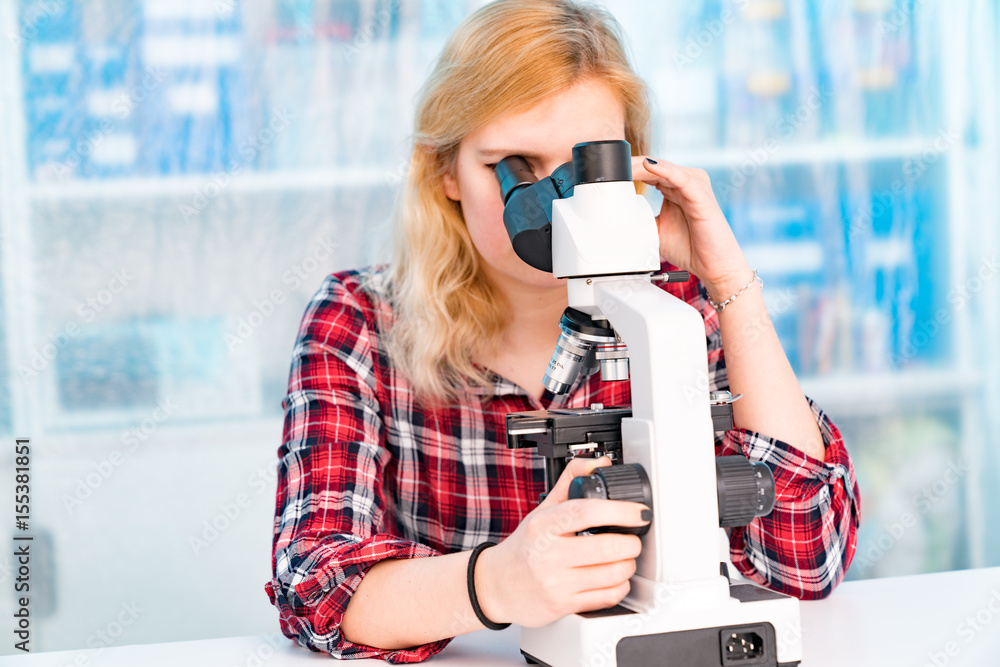 Student girl in microbiology class, learning workshop with microscope