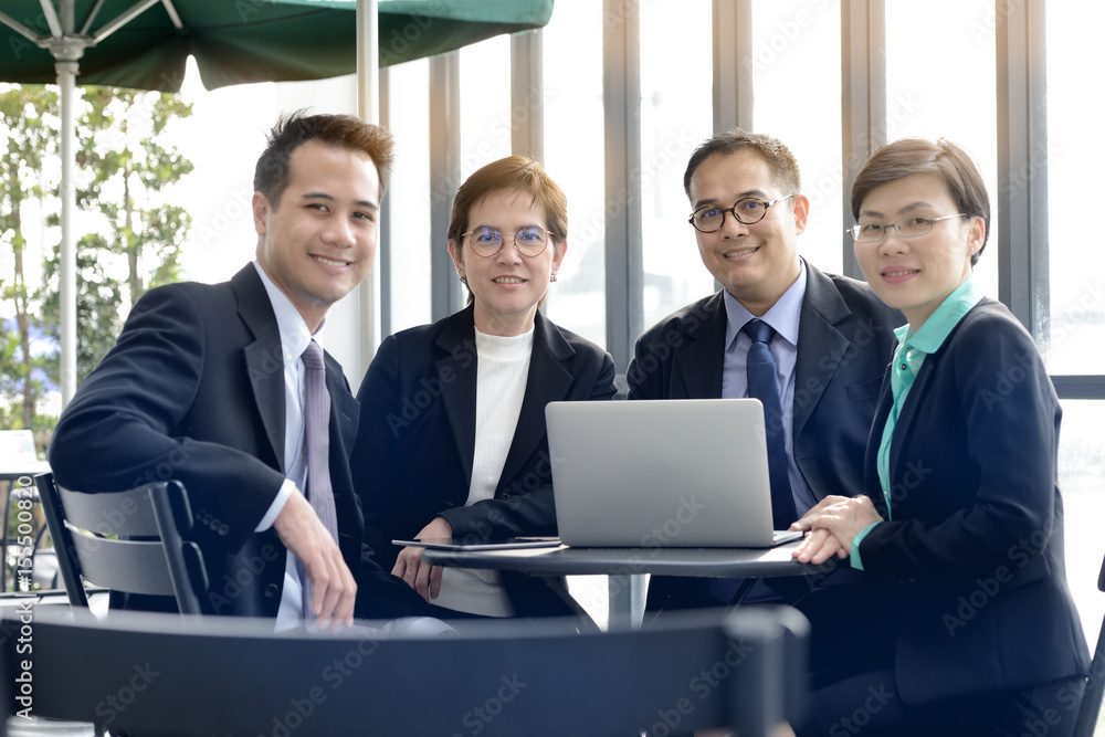 Successful group of business people looking at camera with smiles at outdoor cafe