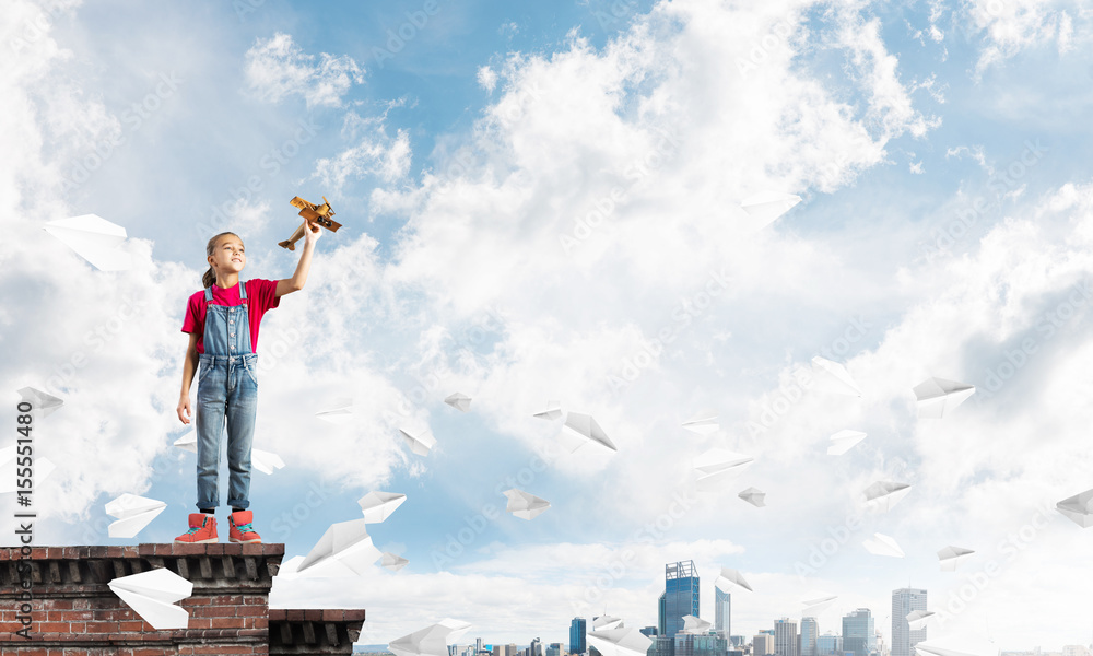 Concept of careless happy childhood with girl dreaming to become pilot