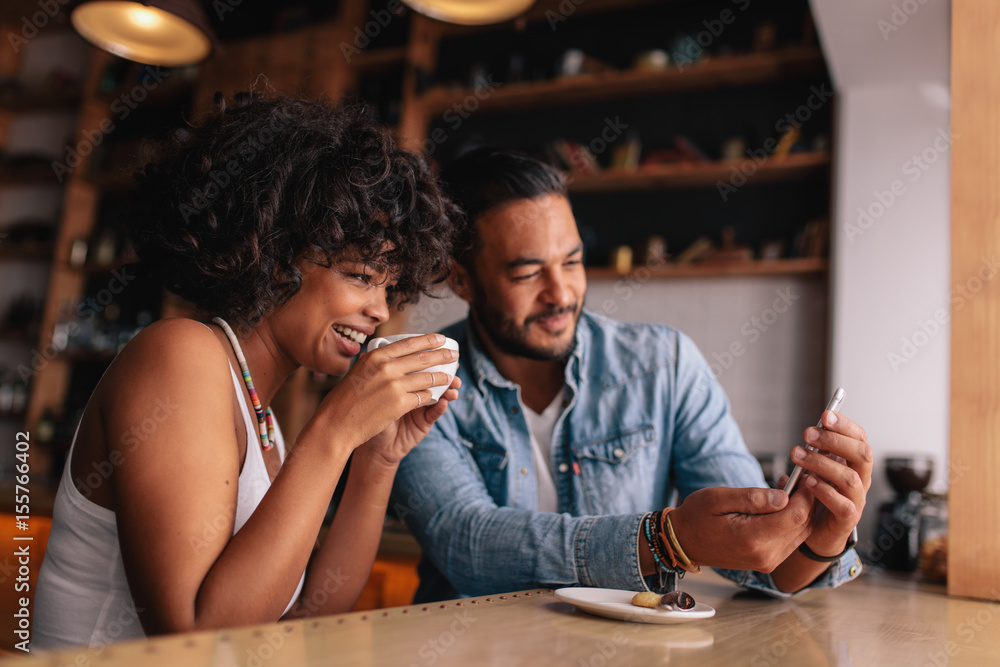 Young couple at coffee shop looking at smart phone