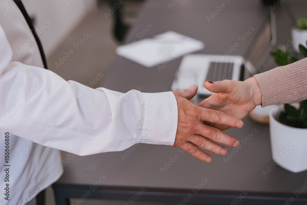 Woman making handshake with business man after closed deal at desk in the office.