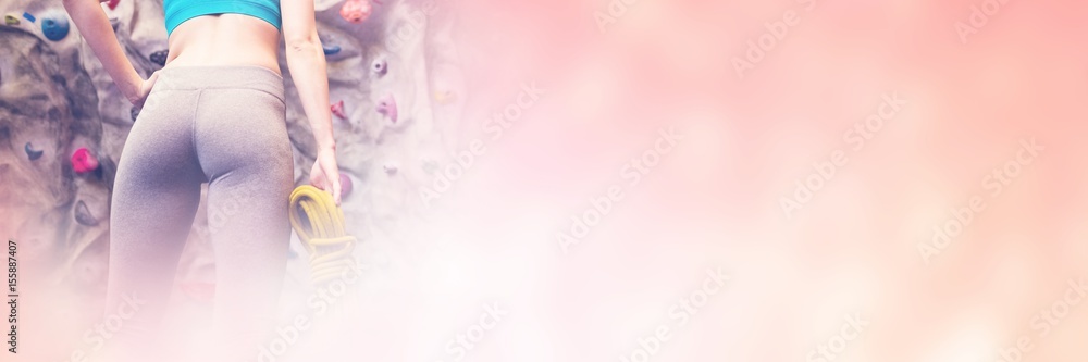 Low angle view of woman looking up at rock climbing wall