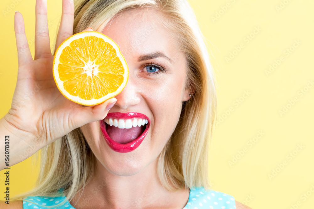 Happy young woman holding oranges halves