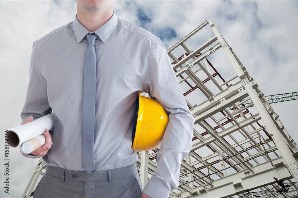 Architect close to a building with his hard hat and plans