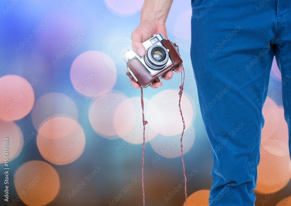 Hand holding camera with sparkling light bokeh background