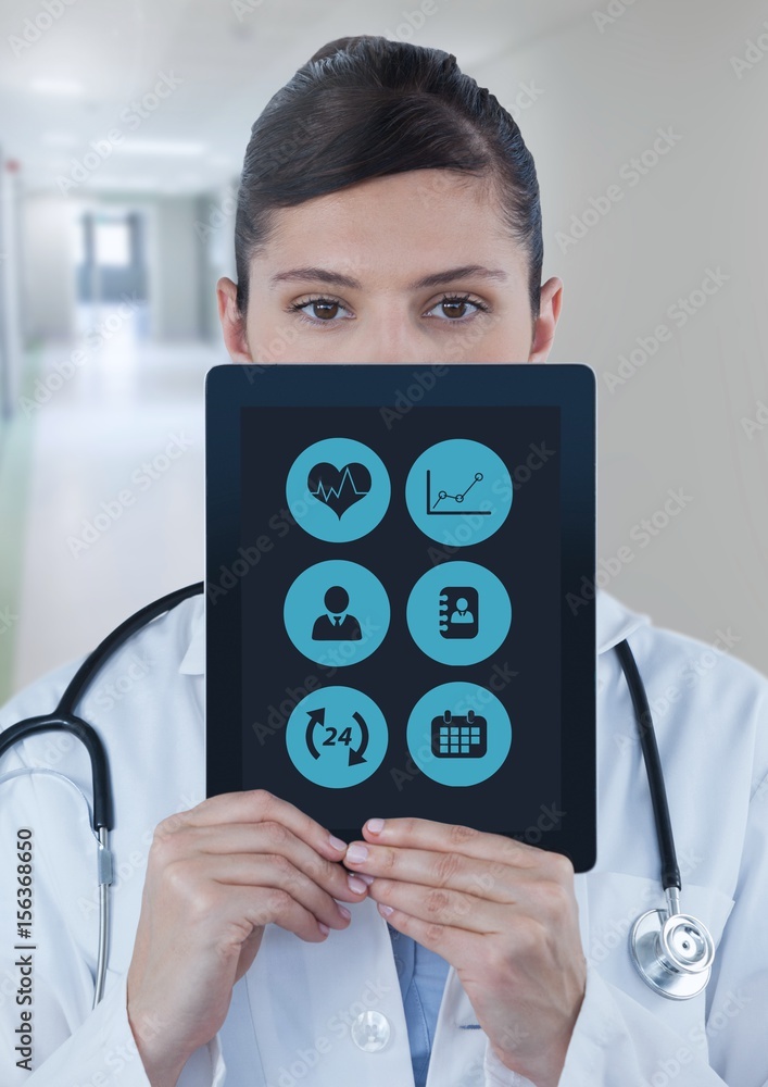 Doctor holding tablet with apps over face in corridor