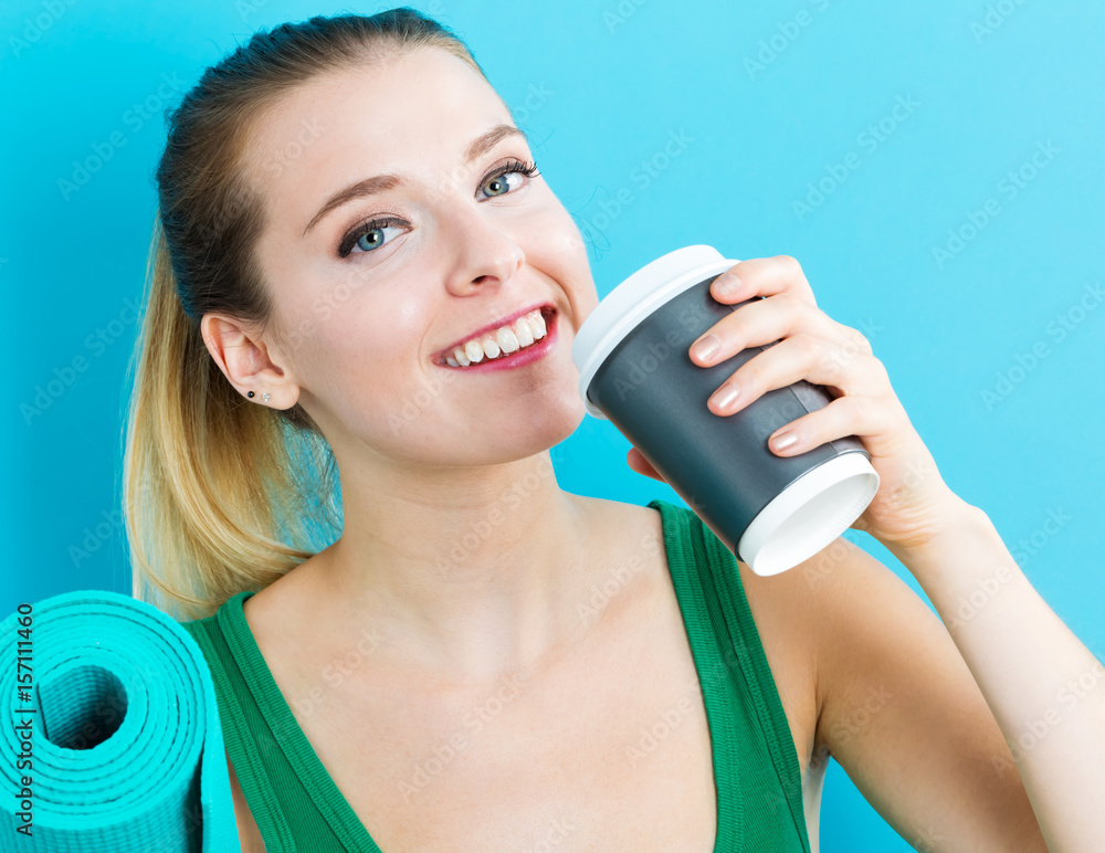 Woman holding coffee cup and yoga mat